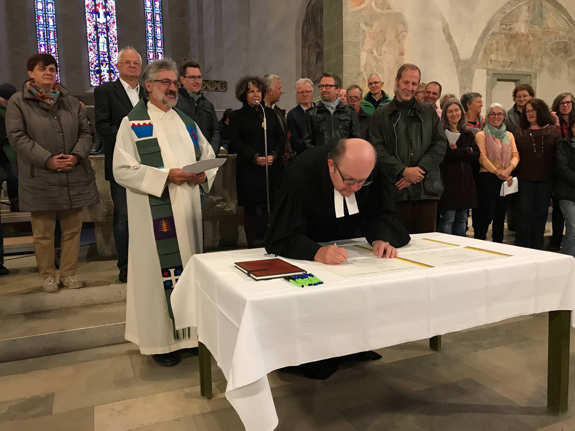 Mit der Unterzeichnung der Ravensburger Erklärung begann die intensive Diskussion um die Ökumene im Schussental. Links vorne (stehend) Pfarrer Hermann Riedle, am Tisch sein evangelischer Kollege Martin Henzler-Hermann