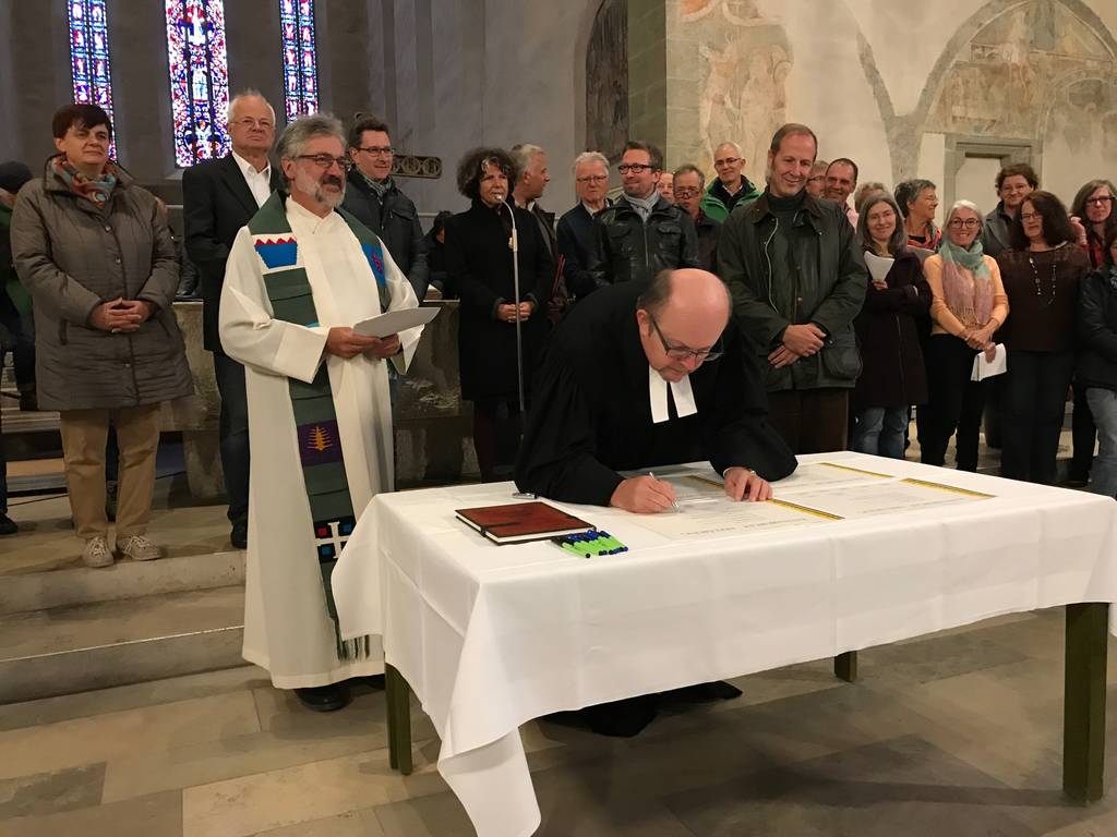 Mit der Unterzeichnung der Ravensburger Erklärung begann die intensive Diskussion um die Ökumene im Schussental. Links vorne (stehend) Pfarrer Hermann Riedle, am Tisch sein evangelischer Kollege Martin Henzler-Hermann